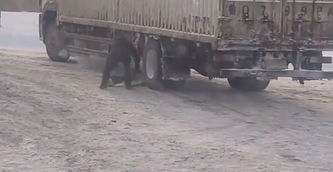 路面积雪车子上坡打滑，交警脱下自己的衣服给司机垫轮胎