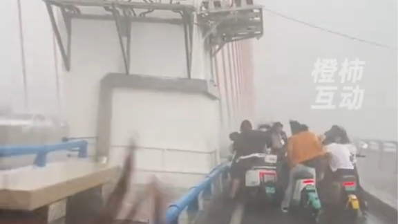 云南景洪遇强对流天气：有市民在桥墩旁躲避大风无法前行