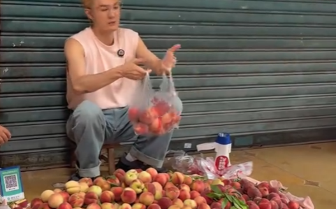 吴克群帮路边摊主卖桃子，拿着喇叭卖力吆喝
