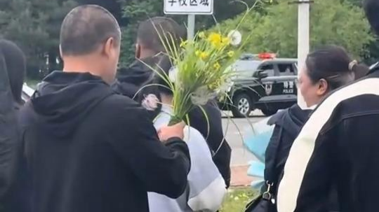 父亲手捧野花在考场外等孩子归来