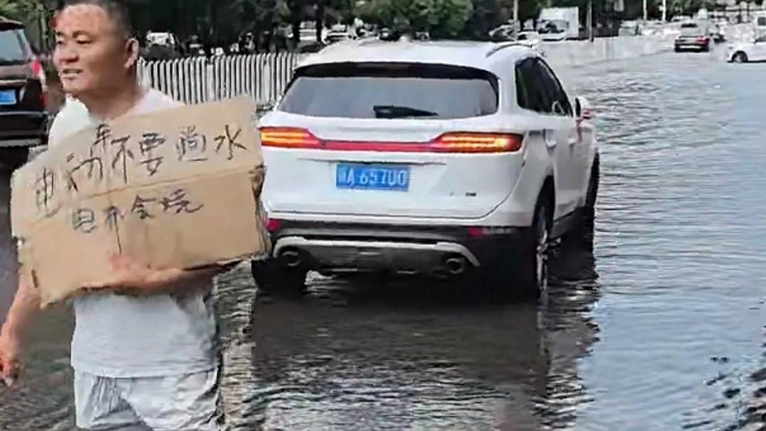 暴雨天电动车老板举牌劝骑车人别蹚水